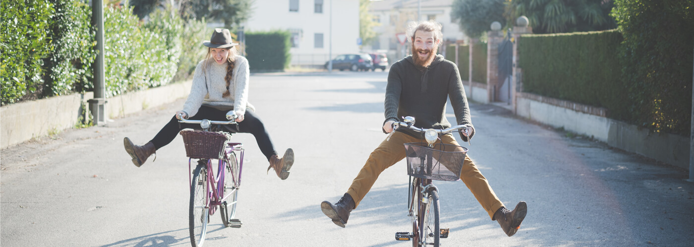 Two joyful people biking down the street